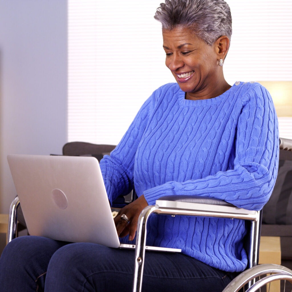 Photo of woman sitting in a wheelchair while using a laptop computer