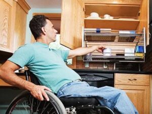 Man in wheelchair reaching into accessible kitchen cabinet
